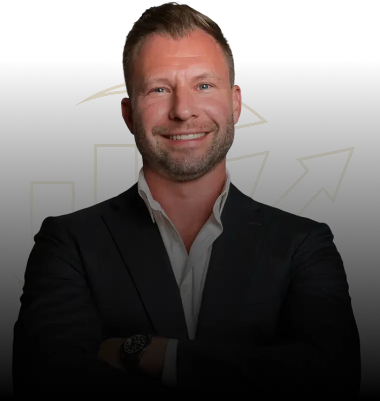 Justin smiling in a dark suit and white open-collar shirt.